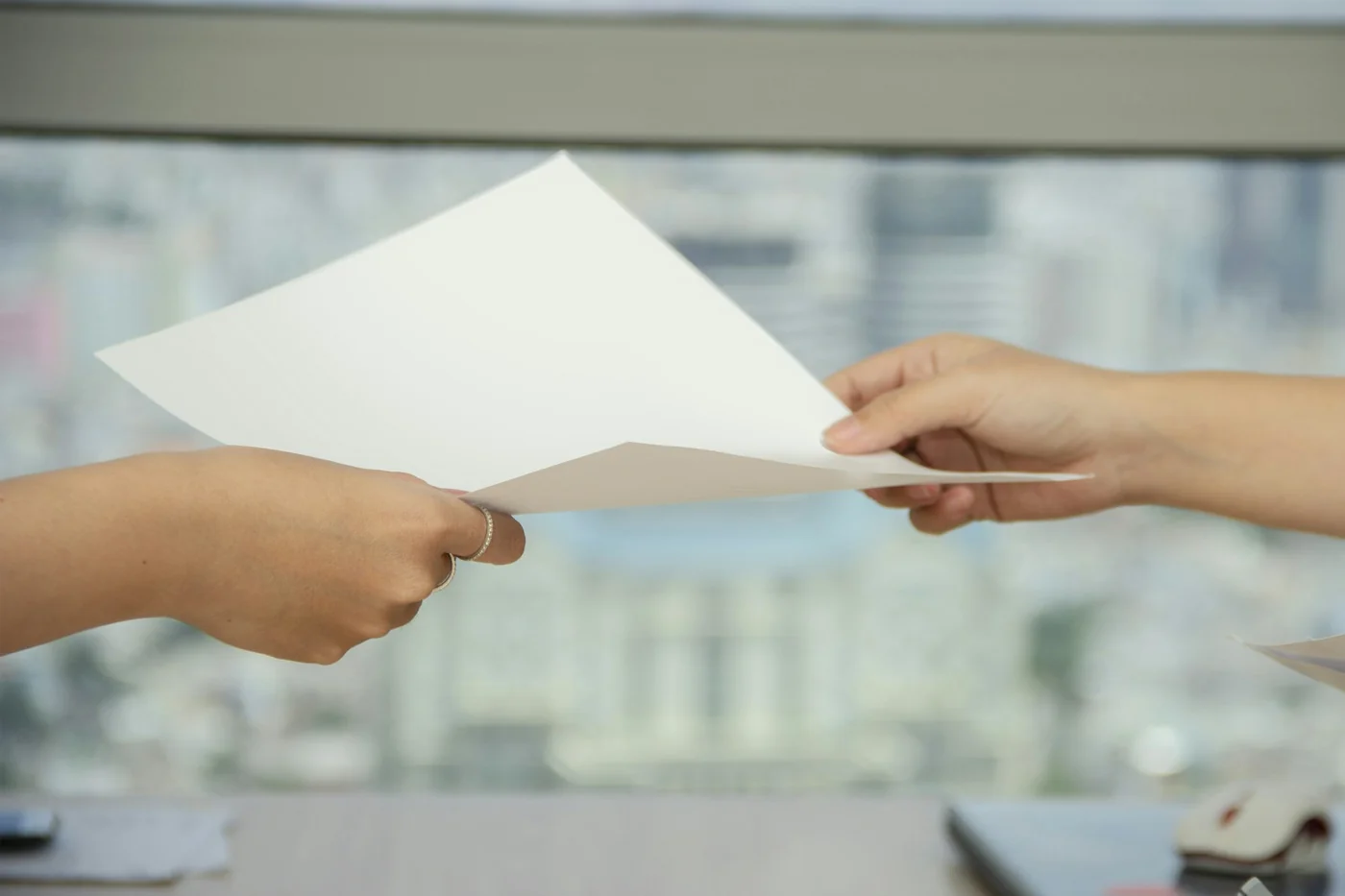 Mãos de duas pessoas entregando folhas de papel.