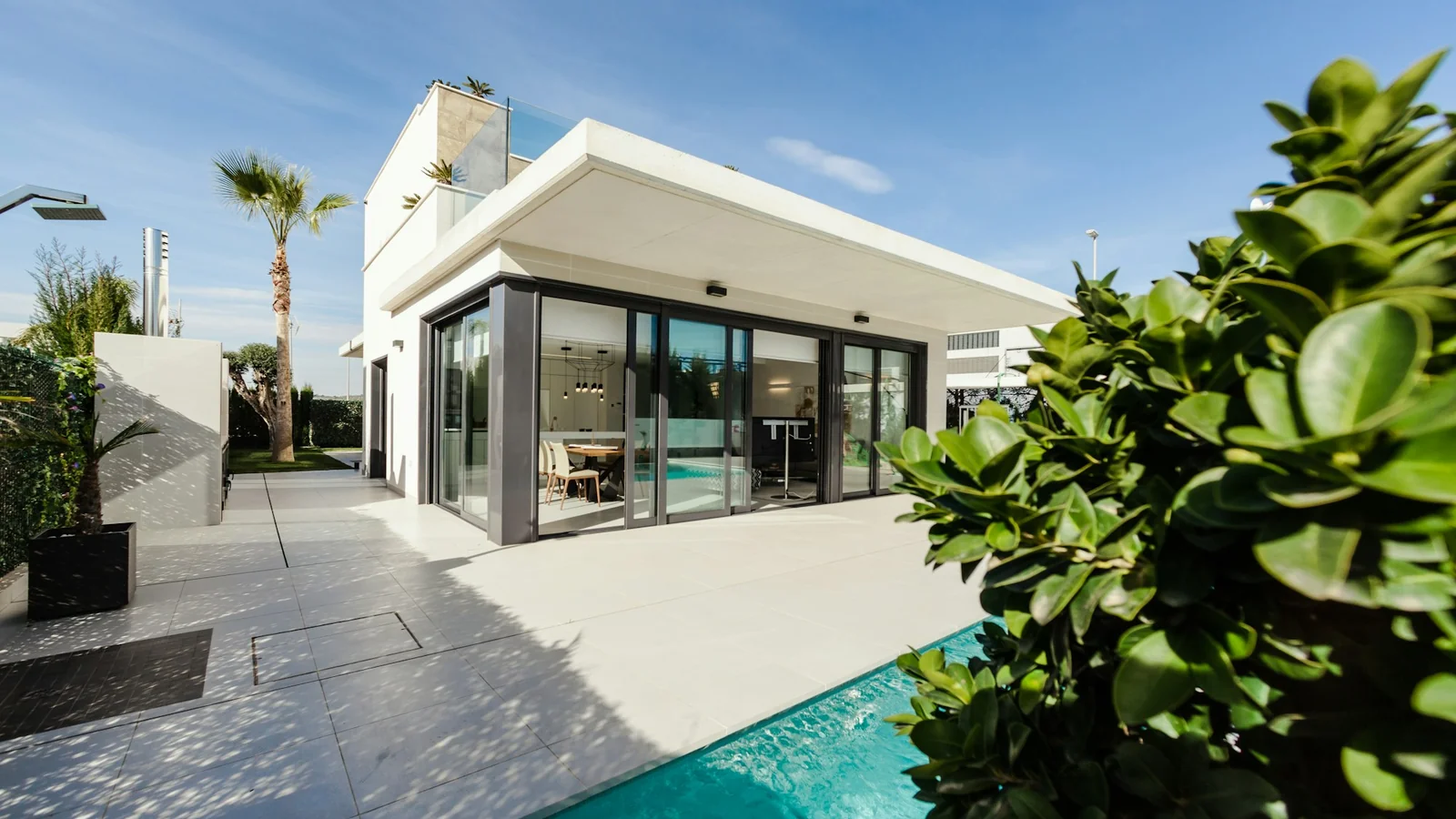 Residência contemporânea com fachada de vidro, jardim e piscina.