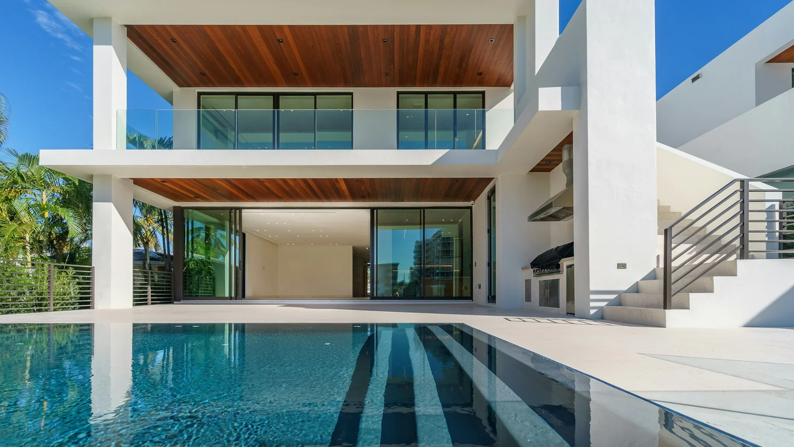 Residência contemporânea com fachada branca, detalhes em madeira e piscina.